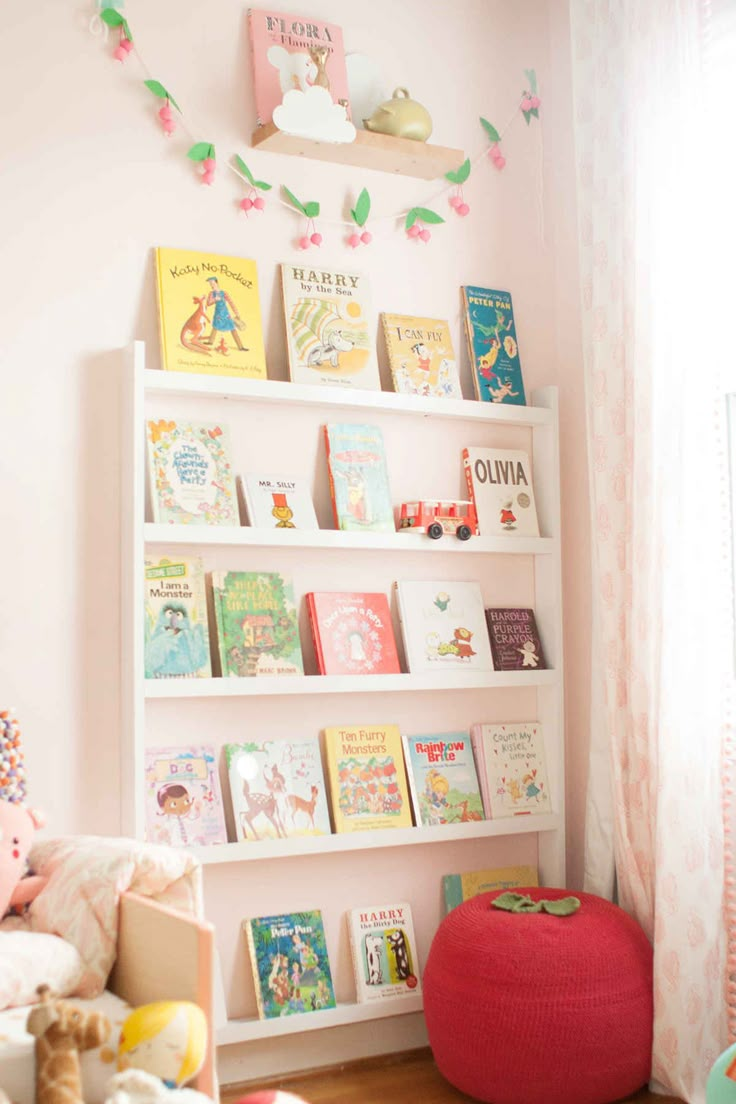 a child's room with pink walls and bookshelves