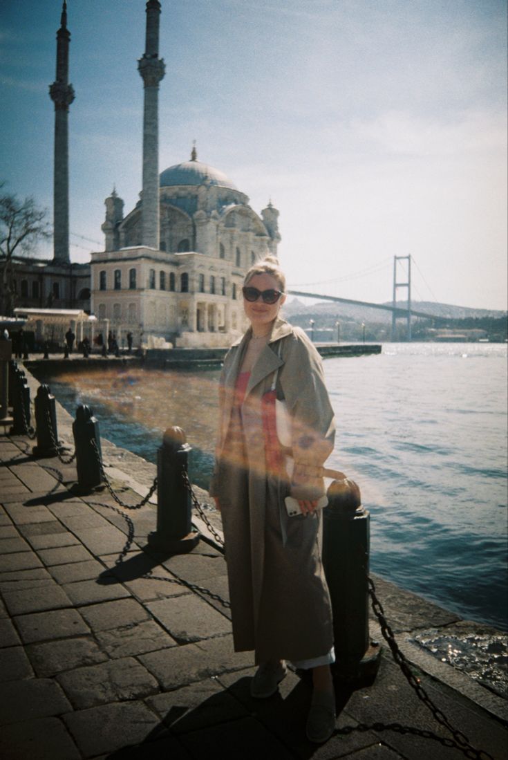 a woman standing next to the water in front of a building