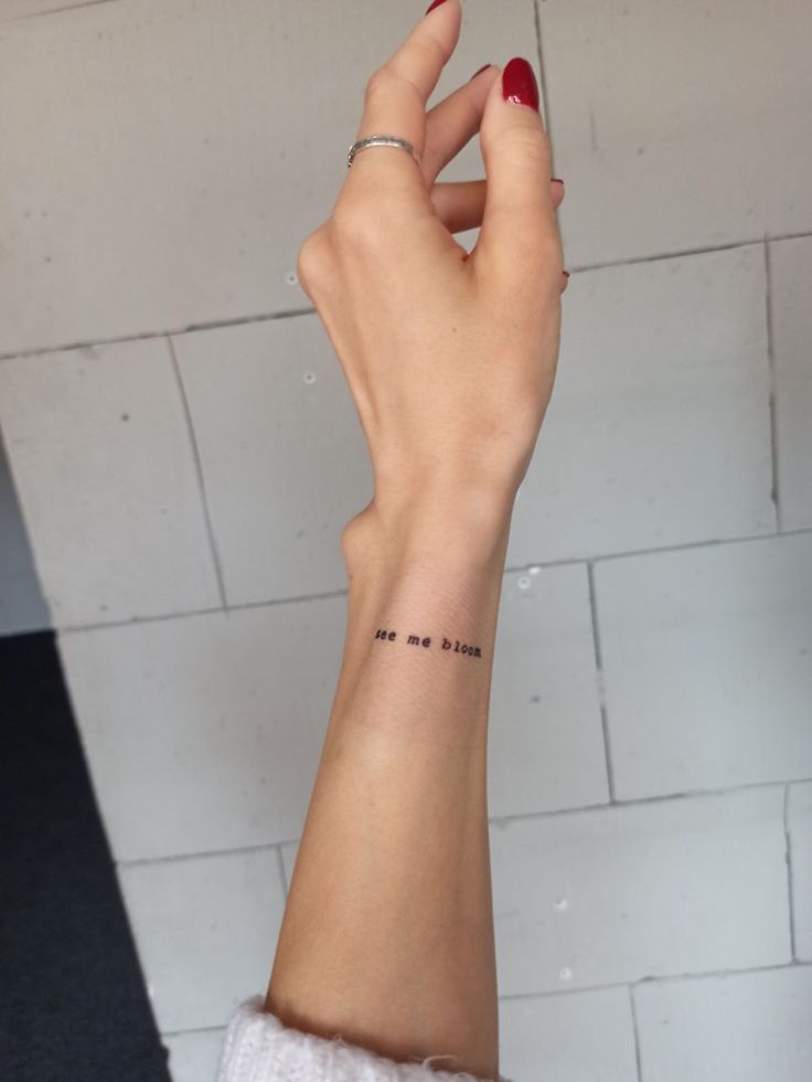 a woman's hand with a small tattoo on her left wrist that reads, no one else