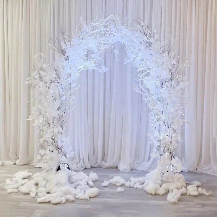 a white wedding arch decorated with snow and branches