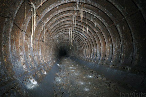 the inside of a tunnel that is very dark and dirty with water running through it