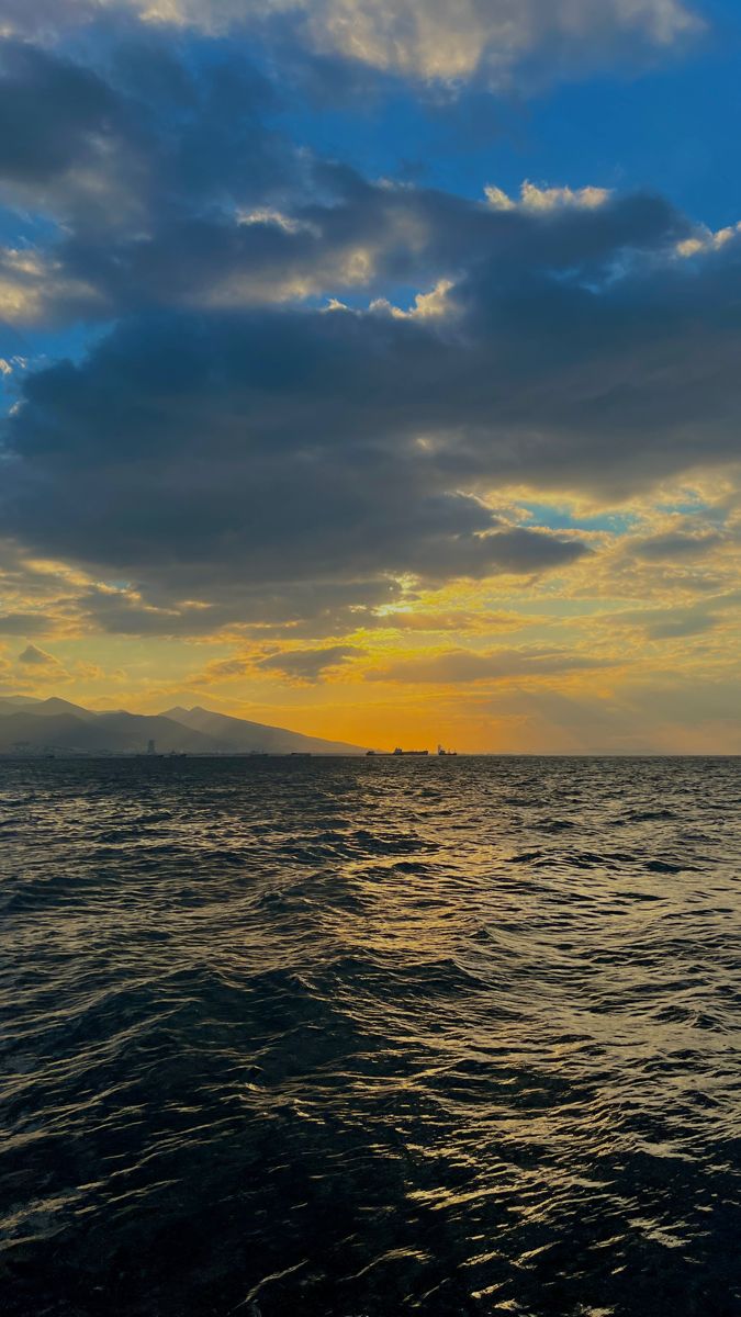 the sun is setting over the ocean with some clouds in the sky and water below