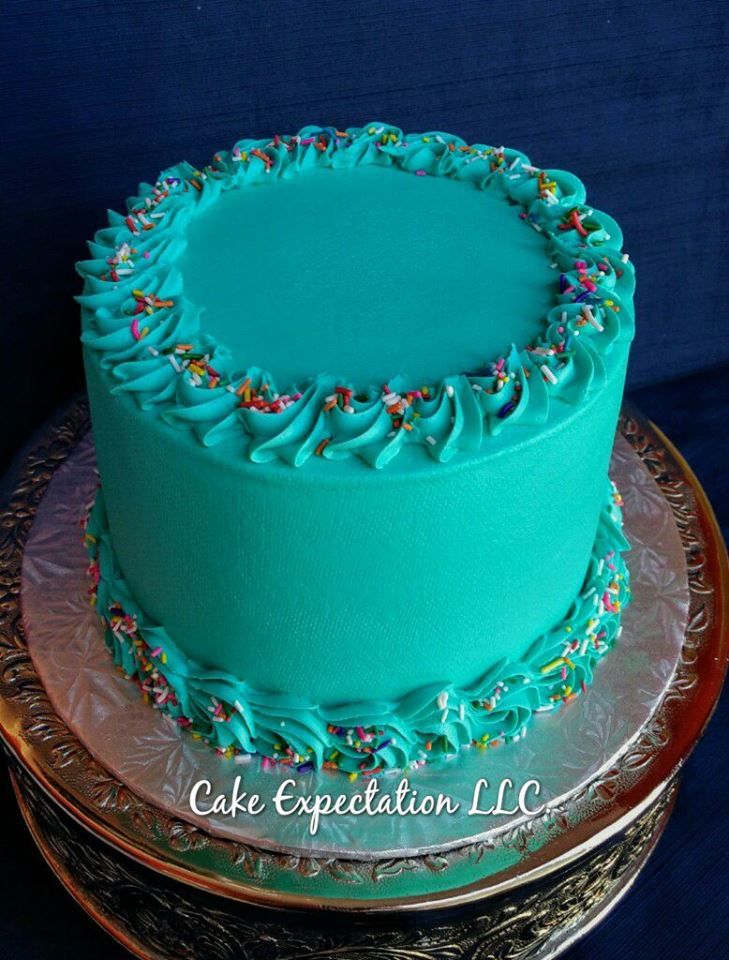 a cake with blue frosting and sprinkles sits on a platter