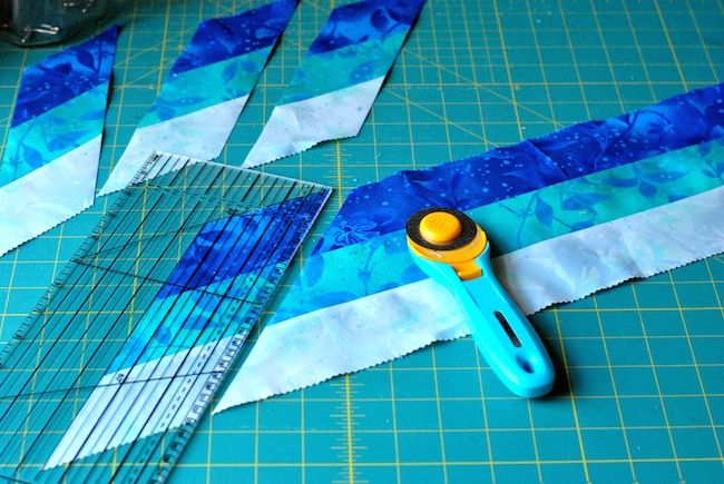 some scissors are laying on top of blue and white strips of paper next to each other