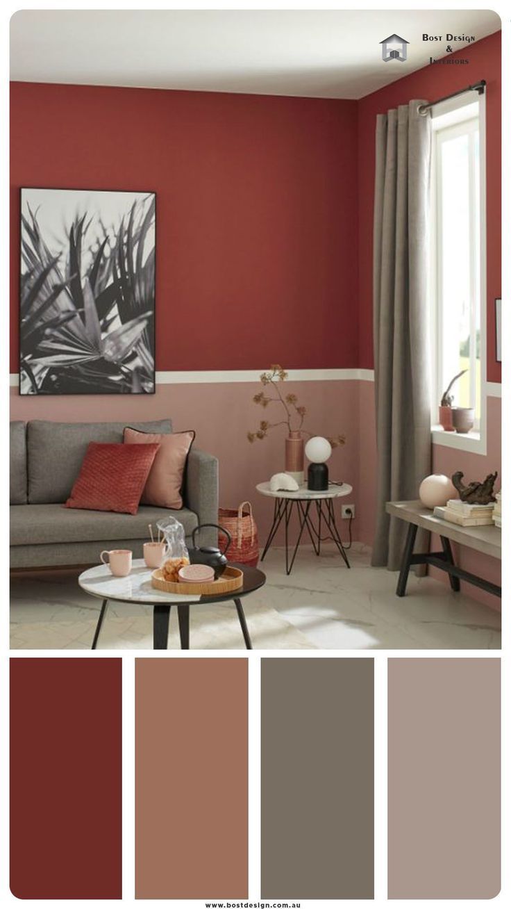 a living room with red walls and grey couches, coffee table and painting on the wall