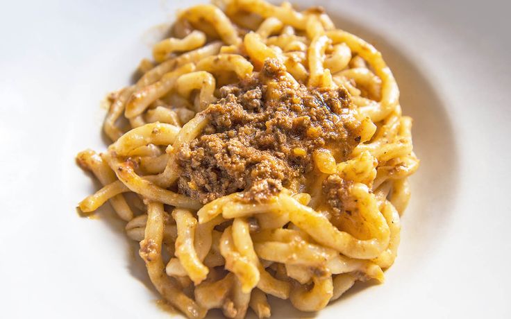 a white plate topped with pasta covered in sauce and ground meat on top of it