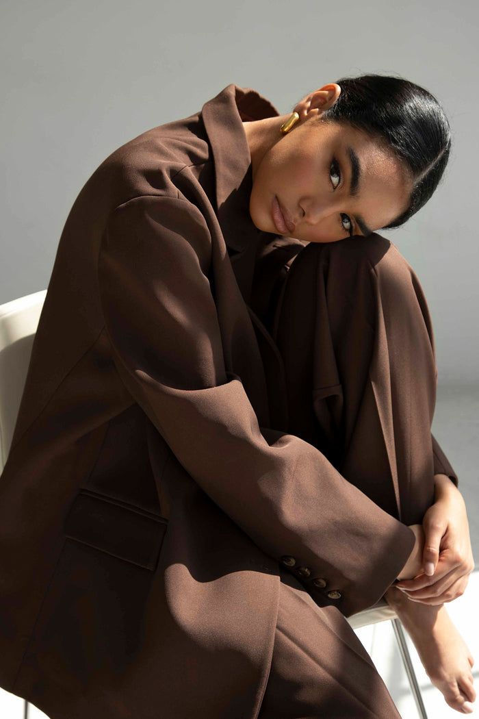 a woman sitting in a chair with her hands on her head and looking off to the side