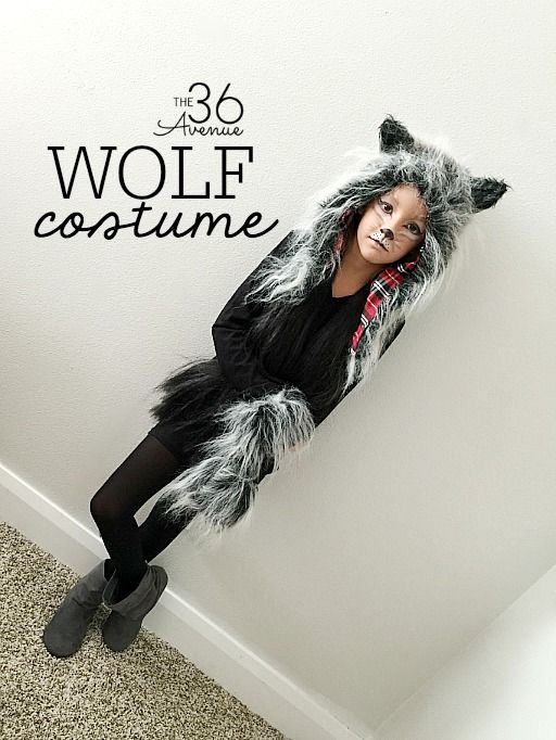 a woman in a wolf costume standing next to a white wall with the words,'38 avenue wolf costume'on it