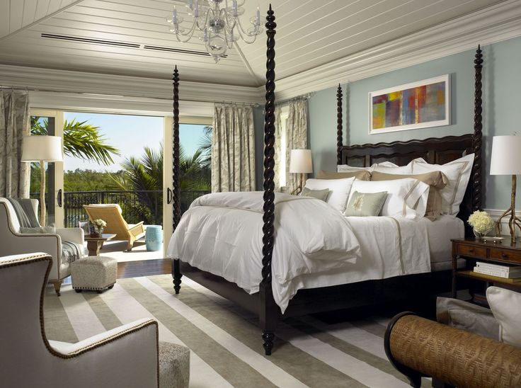 a bedroom with a large bed, chandelier and sliding glass doors leading to an outside patio