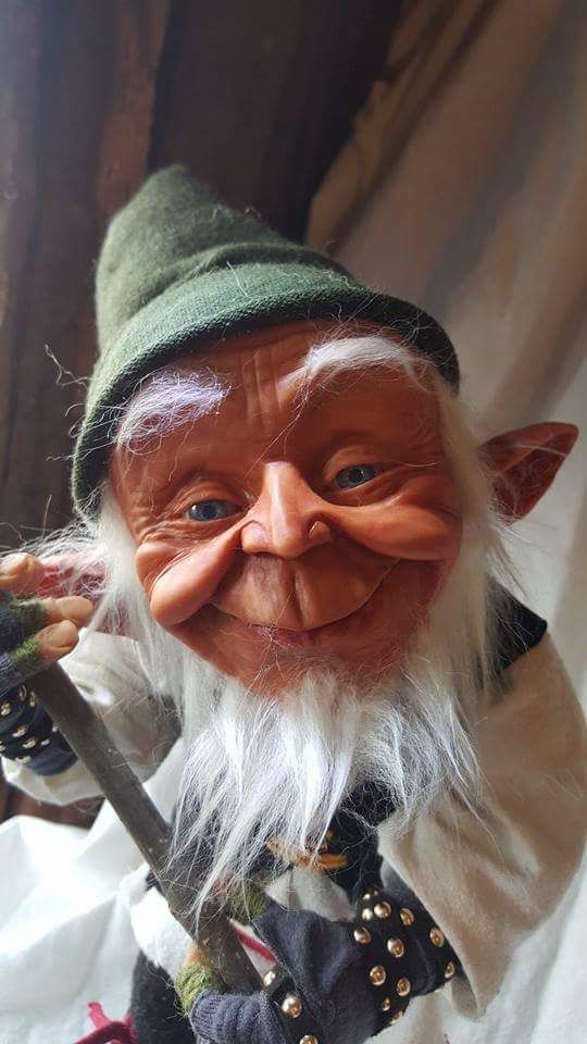 a close up of an old troll with a long white beard and wearing a green hat