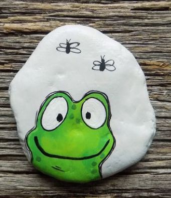 a green frog painted on top of a rock