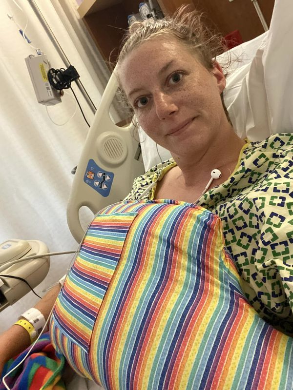 a woman laying in a hospital bed with her arm wrapped around the back of it