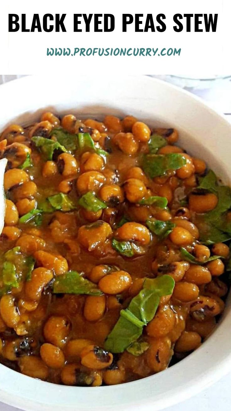 a white bowl filled with black eyed peas stew and garnished with green leaves