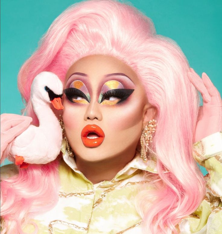 a woman with pink hair and makeup holding a flamingo