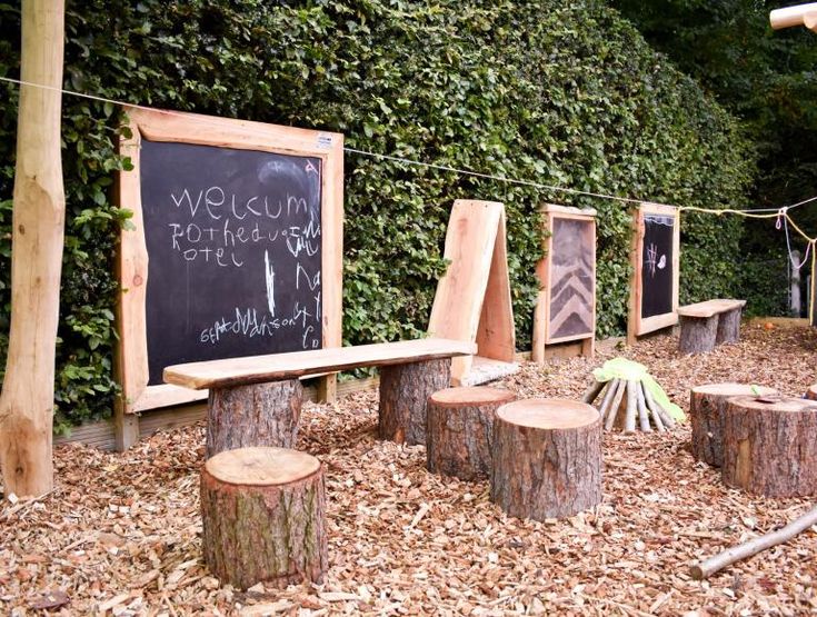 a wooden bench sitting in the middle of a forest next to a chalkboard sign