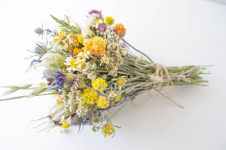 a bouquet of wildflowers is tied up on a white surface