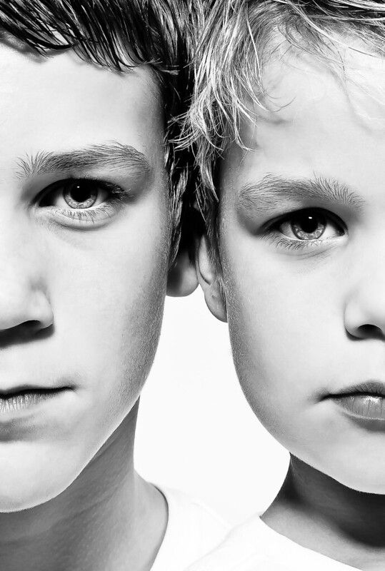 two young boys looking at the camera with their eyes wide open and one has his head turned to the side