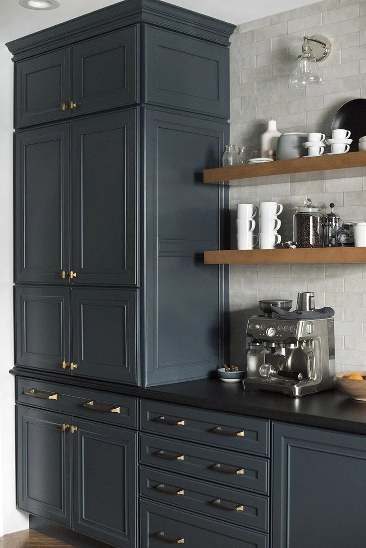 a kitchen with dark blue cabinets and gold knobs on the drawers, coffee maker in the middle