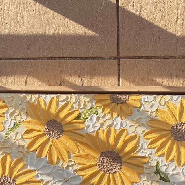 a yellow and white rug with sunflowers on it next to a brick wall