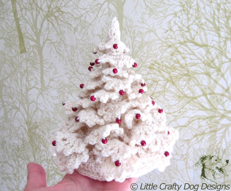 a small crocheted christmas tree is shown in front of a wallpapered background