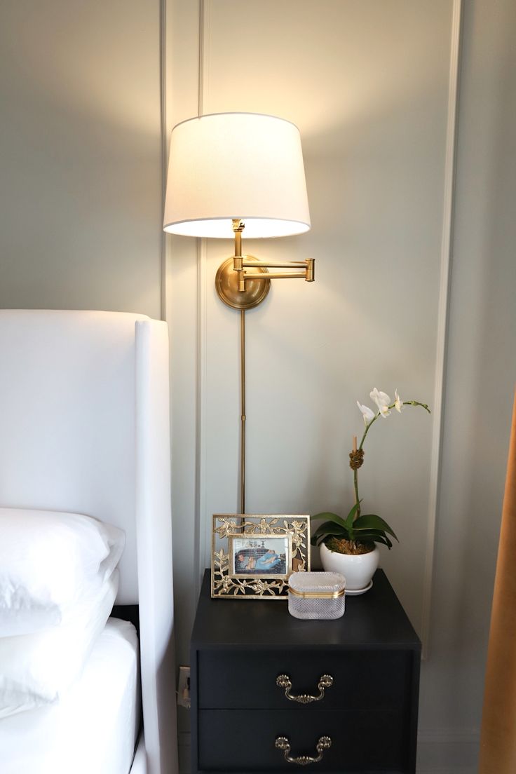 a nightstand with a lamp on it next to a bed