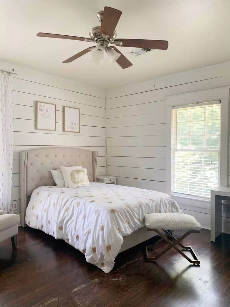 a bed sitting in a bedroom next to a window with blinds on the windowsill