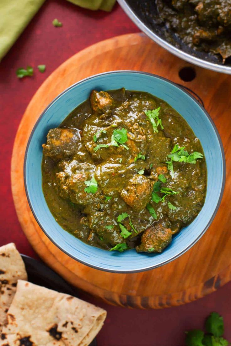 chicken spinach curry served in a bowl with pita crackers on the side