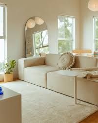 a living room filled with white furniture and lots of windows on the side of it