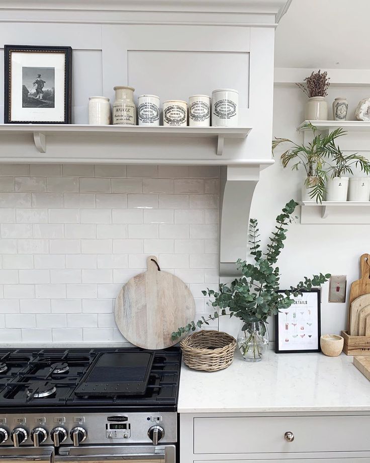 a kitchen with white cabinets and shelves filled with pots and pans on the stove