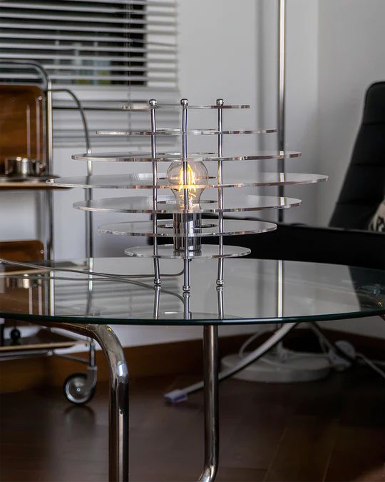 a glass table topped with a light bulb sitting on top of a hard wood floor