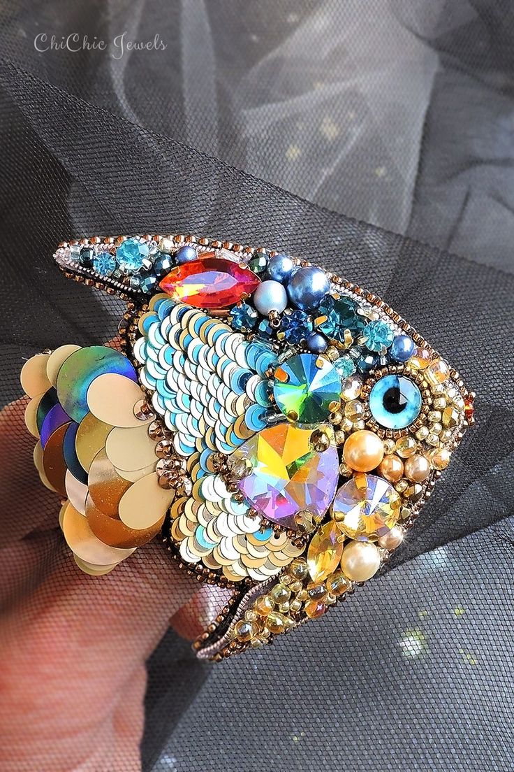 a colorful fish brooch sitting on top of a person's hand