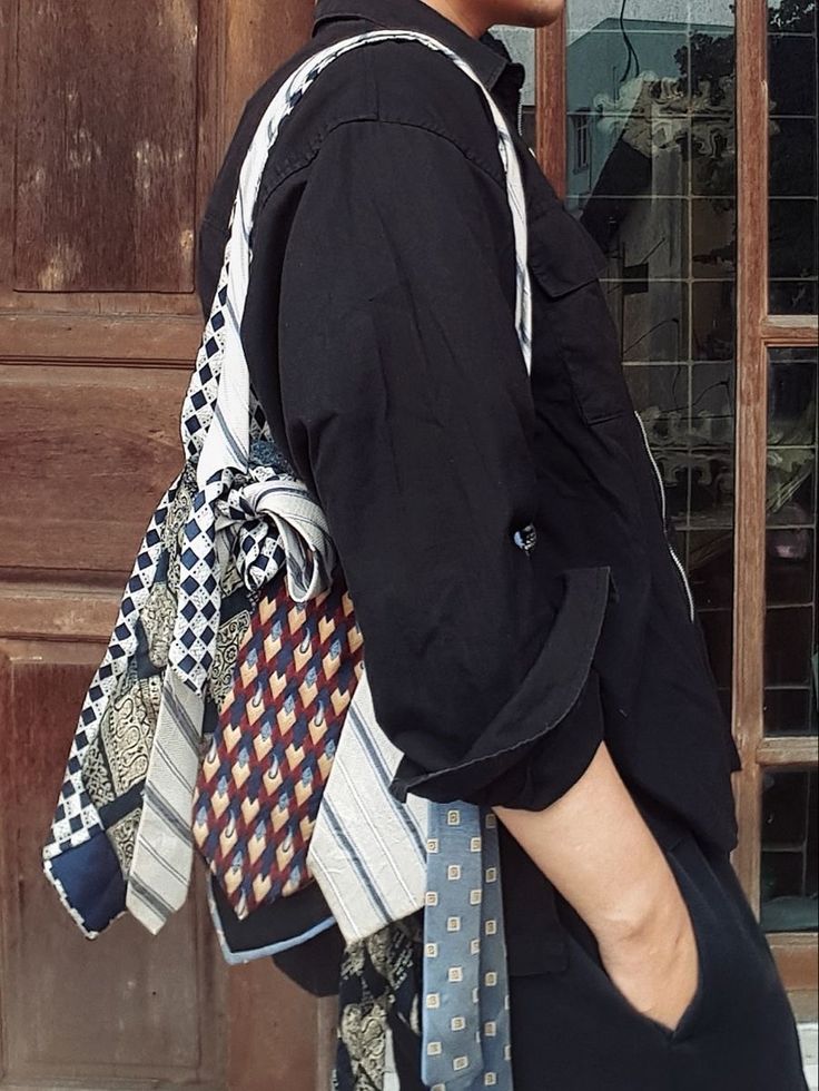 a man in black shirt carrying many ties on his back and wearing glasses with one eye closed