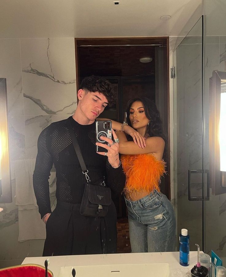 a man and woman taking a selfie in the bathroom with their reflection in the mirror