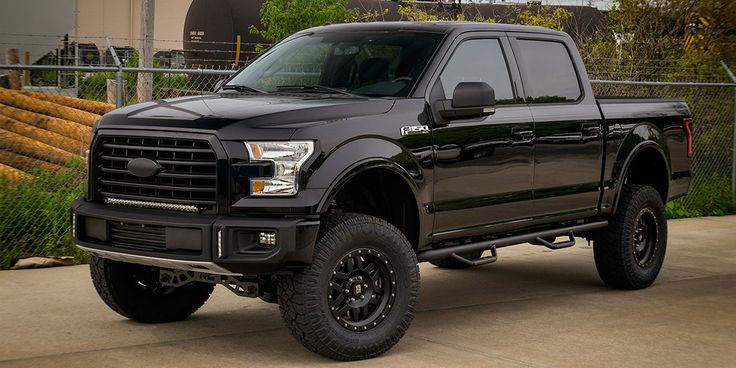 a black truck parked in front of a fence