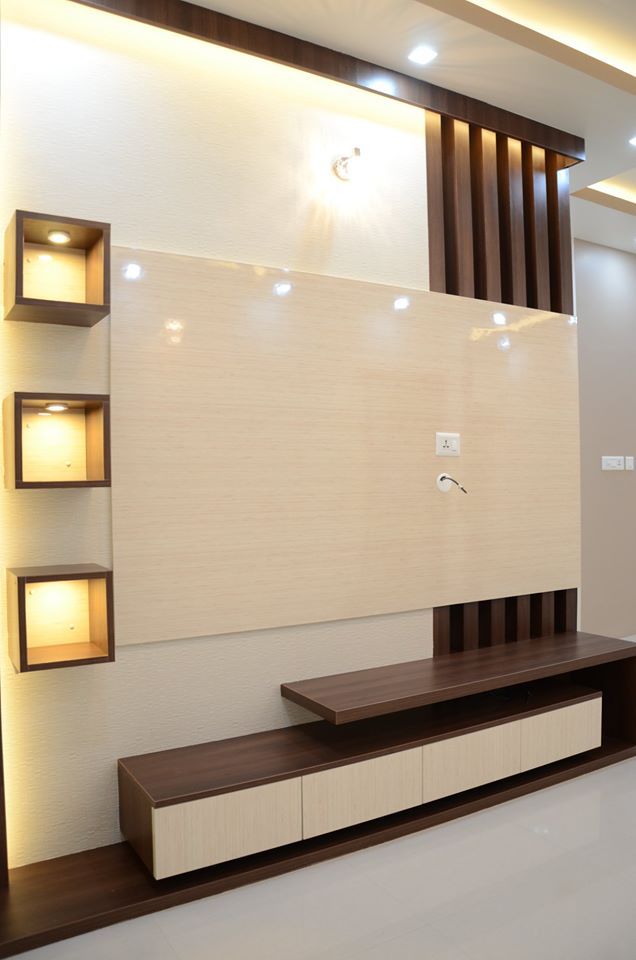 a modern living room with white walls and wooden shelves on the wall, along with recessed lighting