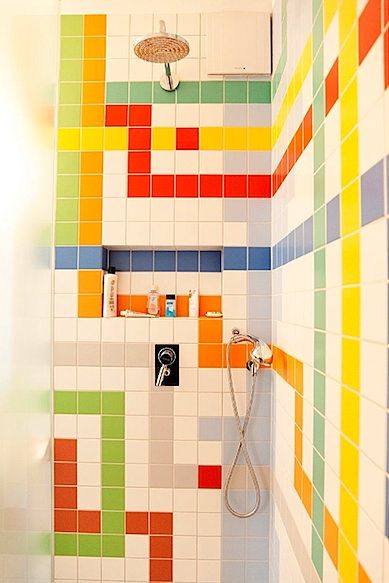 a bathroom with colorful tiles on the wall and shower head mounted to the side of the bathtub