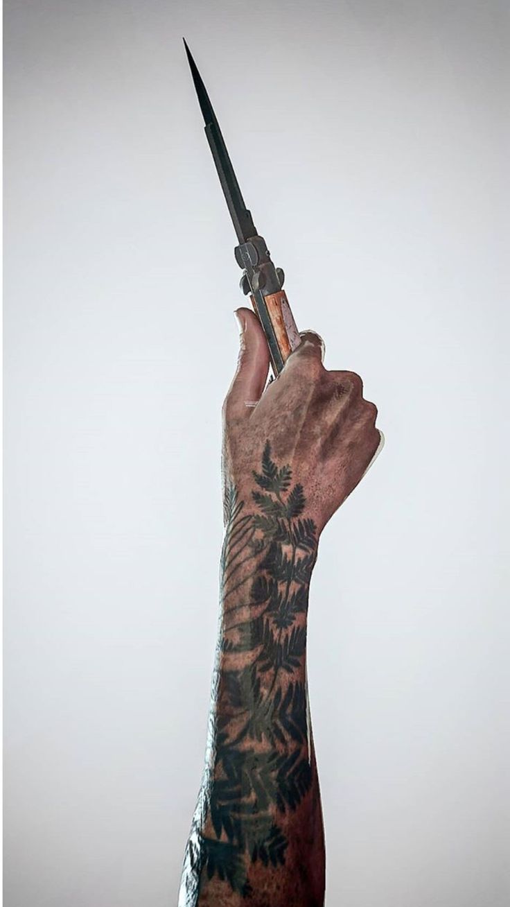 a tattooed hand holding a knife in the air