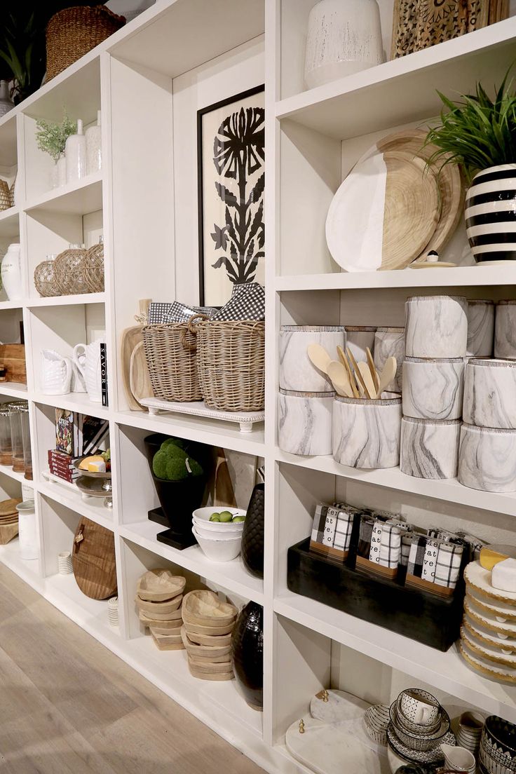 the shelves are filled with baskets, plates and other decorative items in white painted shelving