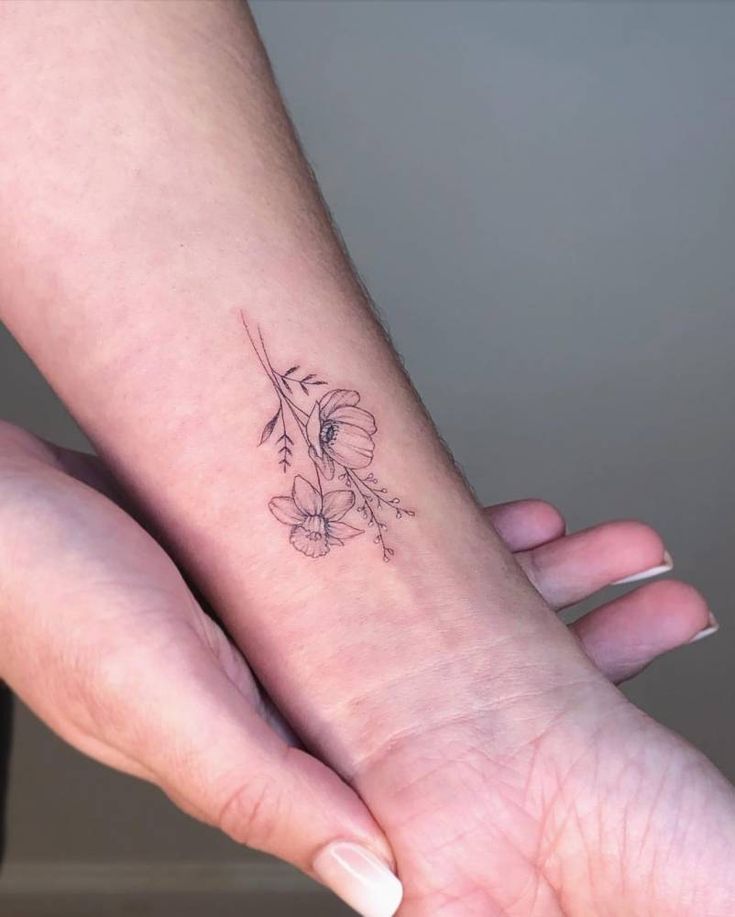 a small flower tattoo on the wrist