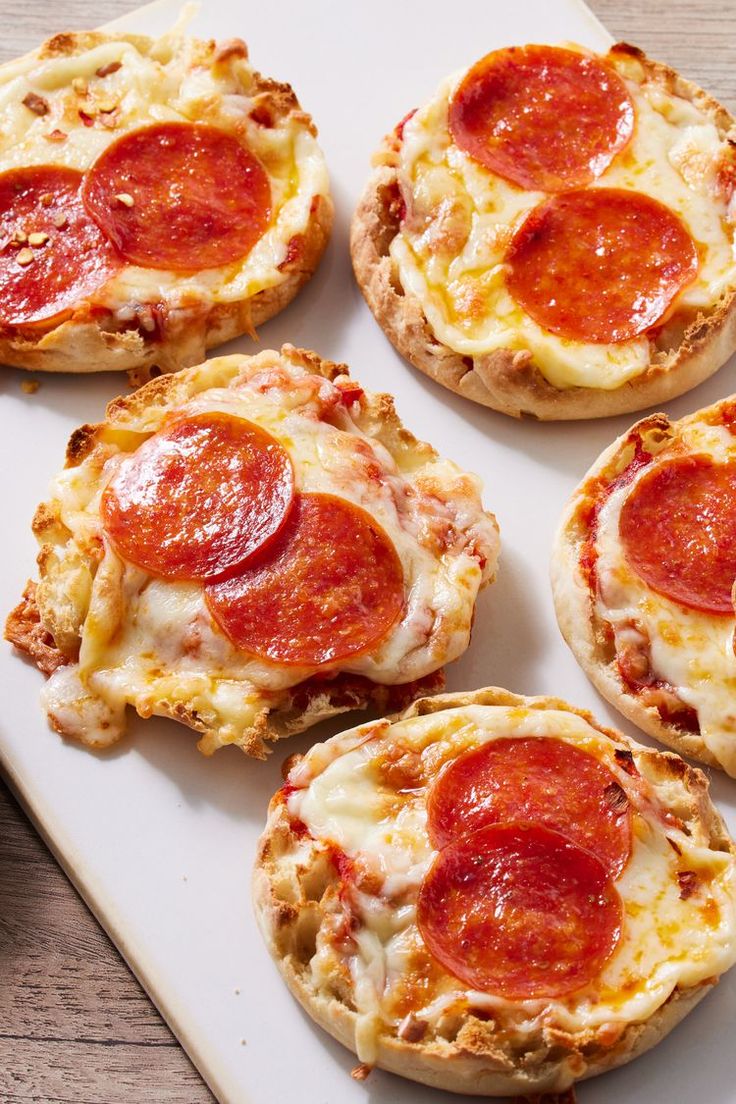 mini pizzas with cheese and pepperoni are on a white tray, ready to be eaten