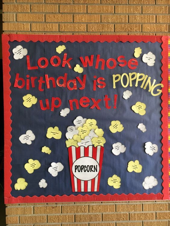 a sign that says look whos birthday is popping up next to popcorn on the wall