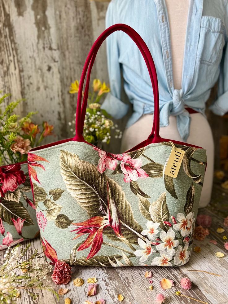 Wanting to get into a relaxed island state of mind? Go for a Tiki-rific Lolita featuring a tropical motif in soft colors and florals.

The Atenti Tiki Lolita is an open tote with a magnetic closure and a large detachable interior pouch measuring 12" wide x 10" high x 3" deep in a matching fabric. Both pieces are fully lined with water resistant taffeta. The outside shell bag features a zippered pocket and an open divided pocket with a cell phone slot. Atenti Lolita measures 17" wide x 11" tall x Tropical Tote Shoulder Bag For Vacation, Tropical Style Tote Shoulder Bag For Vacation, Green Floral Print Beach Bag, Bohemian Floral Print Bags For Vacation, Floral Print Beach Tote Bag, Beach Tote Bag With Floral Print, Floral Print Tote Shoulder Bag For Vacation, Vacation Floral Print Tote Shoulder Bag, Tropical Style Tote Beach Bag For Everyday Use