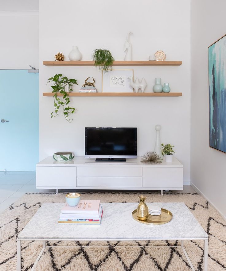 a living room with white furniture and shelves on the wall above it is a tv