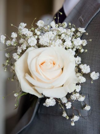 a man in a gray suit with a white rose on his lapel