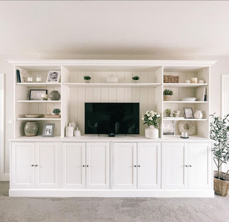 a living room with white cabinets and a flat screen tv on top of the entertainment center