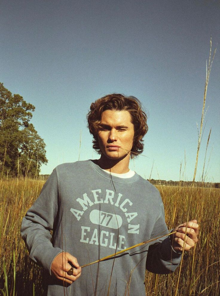 a man standing in tall grass holding a stick