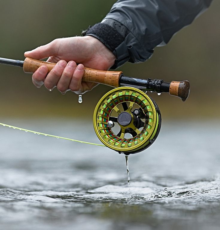 a person is holding a fishing rod and spinning it on the water with their hand