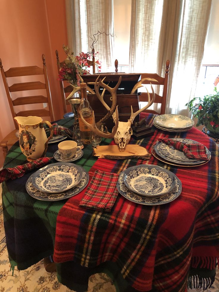 the table is set with dishes and deer antlers