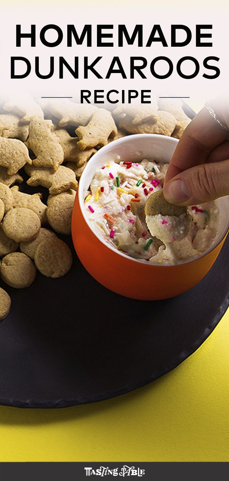 a person dipping food into a bowl on top of a plate with crackers and sprinkles