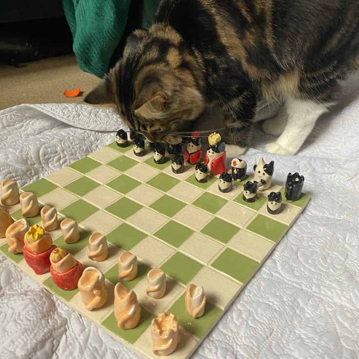 a cat sitting on top of a table next to a chess board and game pieces